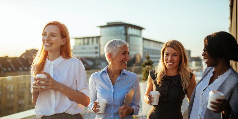 Groupe de femmes d'affaires sur le toit, tenant des gobelets en carton et riant - PER Unique