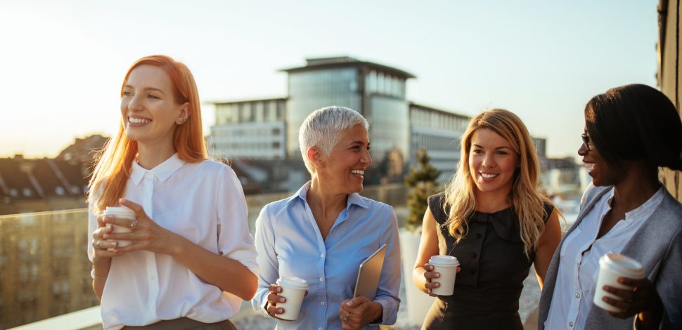Groupe de femmes d'affaires sur le toit, tenant des gobelets en carton et riant - PER Unique