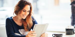 Une femme souriante regardant le rapport sur la santé mentale en Europe sur sa tablette