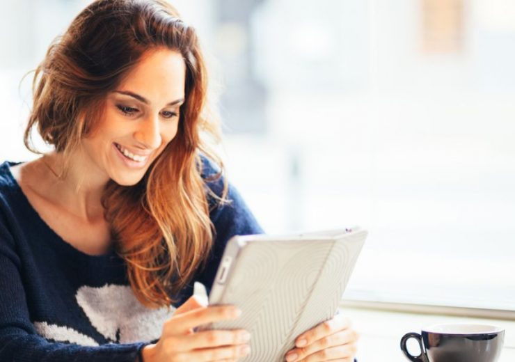 Une femme souriante regardant le rapport sur la santé mentale en Europe sur sa tablette