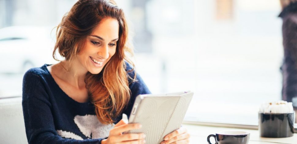 Une femme souriante regardant le rapport sur la santé mentale en Europe sur sa tablette