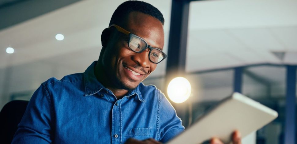 Un homme portant des lunettes regardant le rapport sur la santé mentale en Afrique sur sa tablette Un homme portant des lunettes regardant le rapport sur la santé mentale en Afrique sur sa tablette