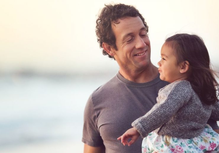 Un père tenant sa fille dans les bras sur la plage - santé mentale
