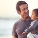 Un père tenant sa fille dans les bras sur la plage - santé mentale