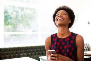 Une femme souriante sur son téléphone et découvrant les versements volontaires