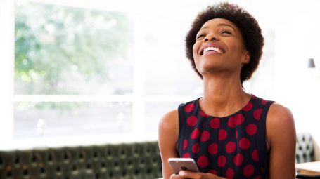 Une femme souriante sur son téléphone et découvrant les versements volontaires