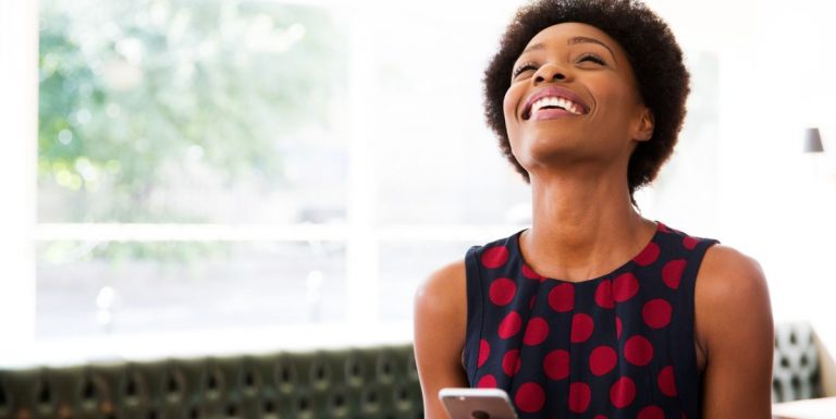 Une femme souriante sur son téléphone et découvrant les versements volontaires