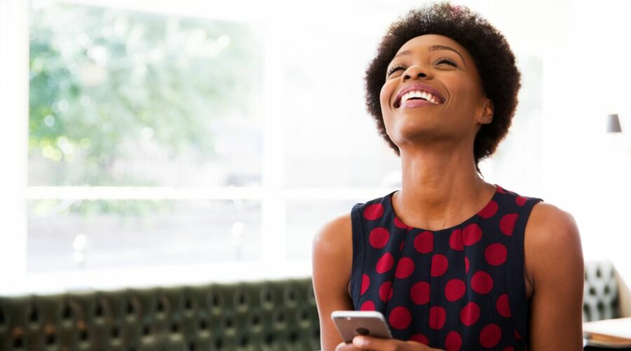 Une femme souriante sur son téléphone et découvrant les versements volontaires