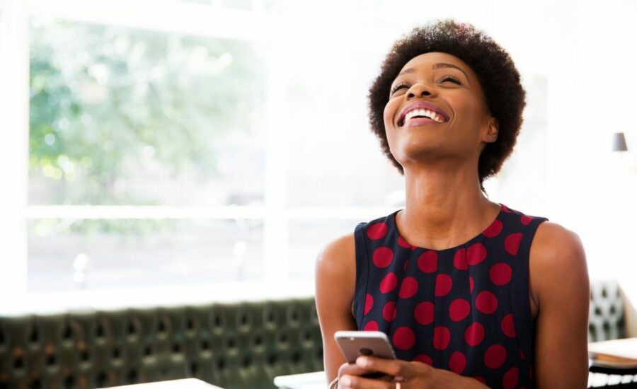 Une femme souriante sur son téléphone et découvrant les versements volontaires