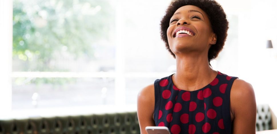 Une femme souriante sur son téléphone et découvrant les versements volontaires