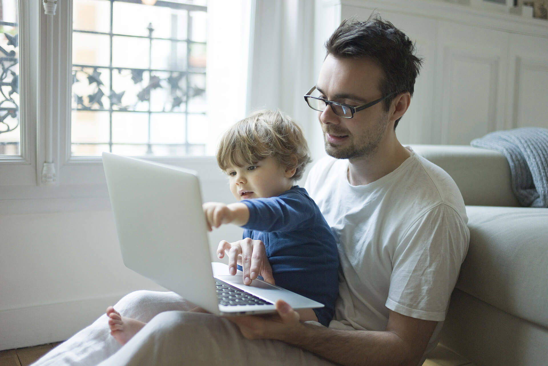 Un père avec son fils sur les genoux devant un ordinateur portable
