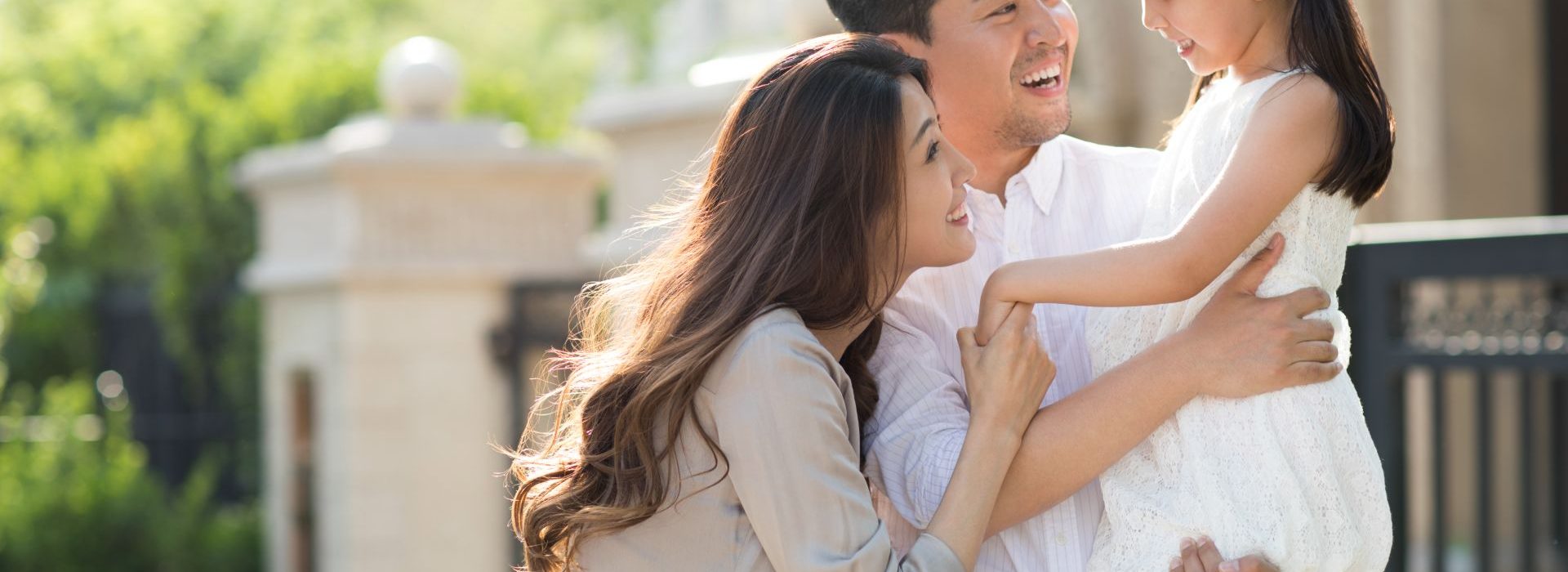 Deux parents tenants leur fille dans les bras en souriant dans la rue