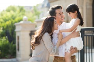 Deux parents tenants leur fille dans les bras en souriant dans la rue