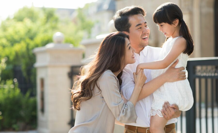 Deux parents tenants leur fille dans les bras en souriant dans la rue