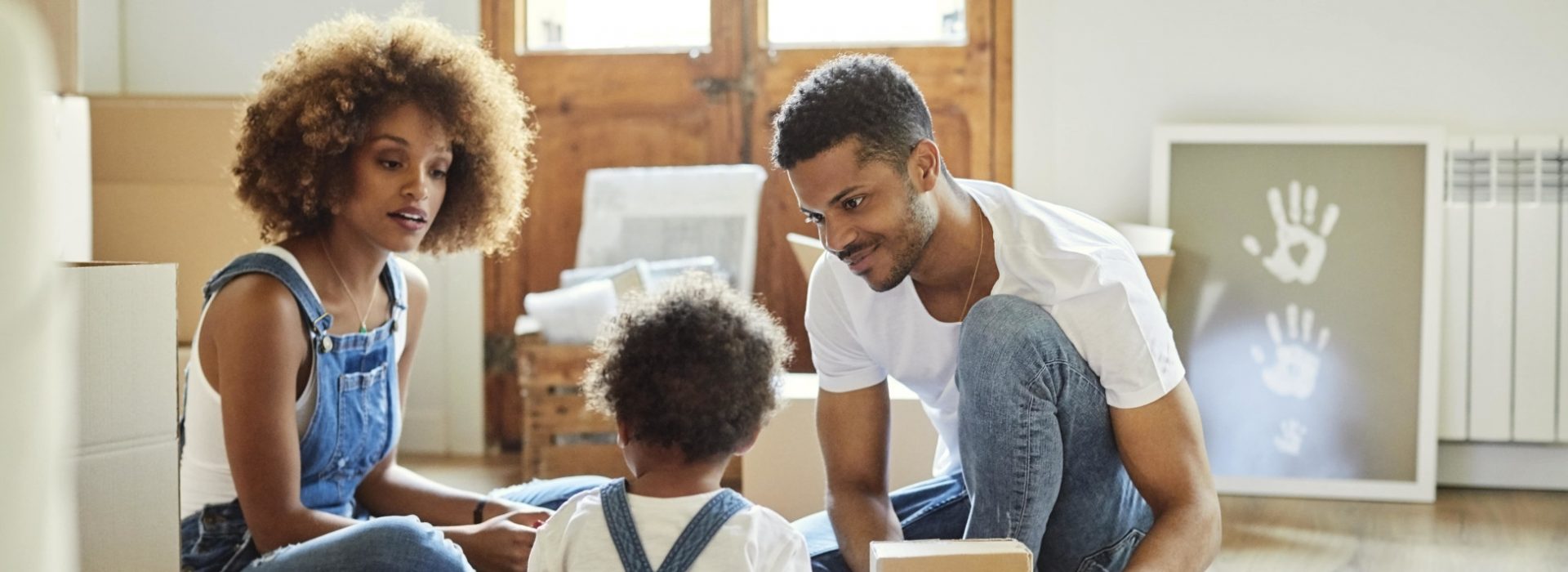 Deux parents, assis par terre et déballant des cartons avec leur enfant