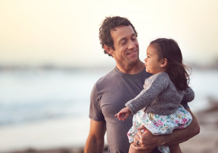 Un père tenant sa fille dans les bras sur une plage