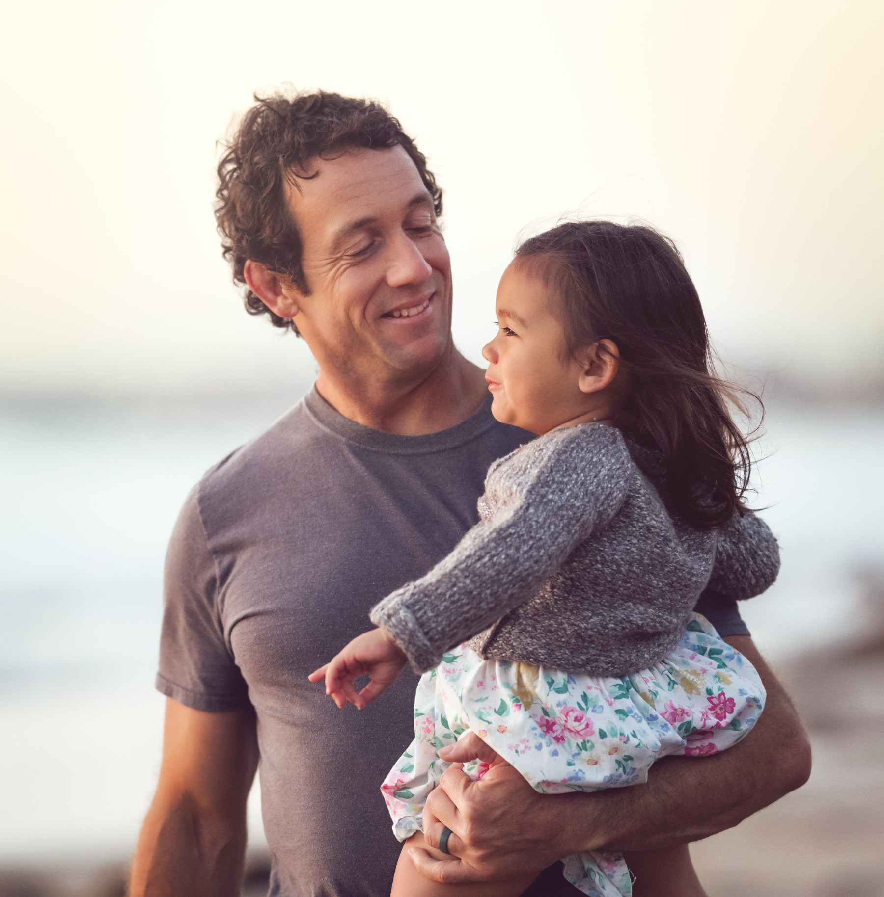Un père tenant sa fille dans les bras sur une plage