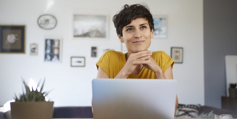 Femme pensante et souriante devant son ordinateur après avoir préparer son hospitalisation - hospiway