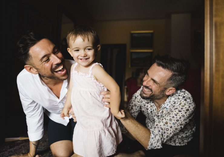Deux hommes souriants et jouant avec leur petite fille - quijeprotege