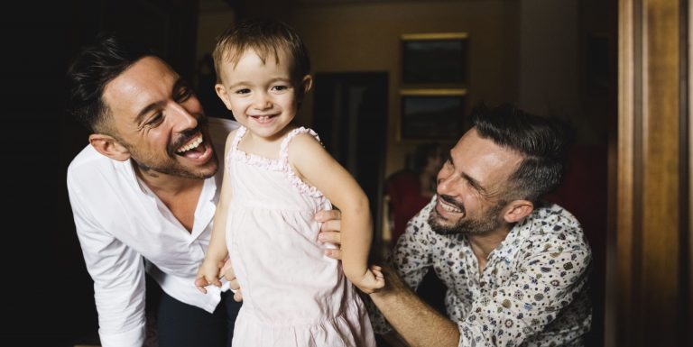 Deux hommes souriants et jouant avec leur petite fille - quijeprotege