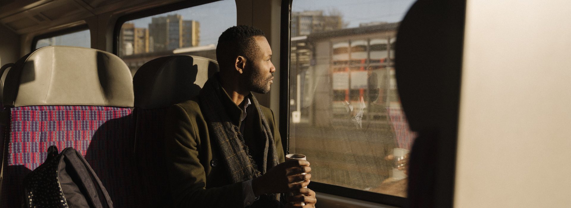 Un homme dans le train regardant la vue avec son café à la main