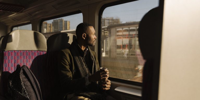 Un homme dans le train regardant la vue avec son café à la main - assistance incidents voyage