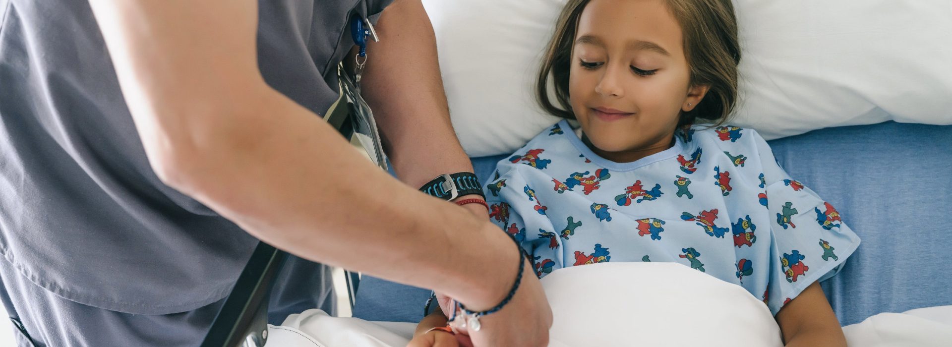 Une petite fille dans un lit d'hôpital avec un médecin qui lui met un bracelet
