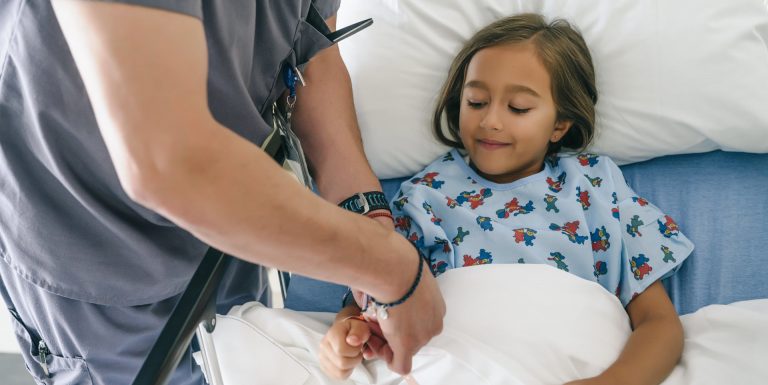 Une petite fille dans un lit d'hôpital avec un médecin qui lui met un bracelet