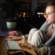 Une femme portant un plaid devant son ordinateur la nuit s'informant sur la maladie de l'endométriose