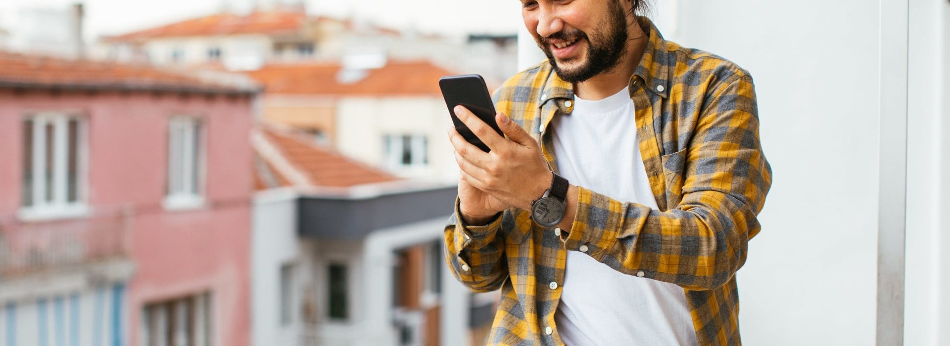 Un homme sur son balcon avec son téléphone dans la main sur l'application AXA épargne salariale