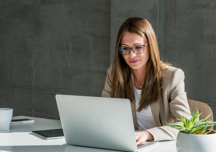 Une femme portant des lunettes au bureau devant son ordinateur sur son espace client entreprise épargne retraite