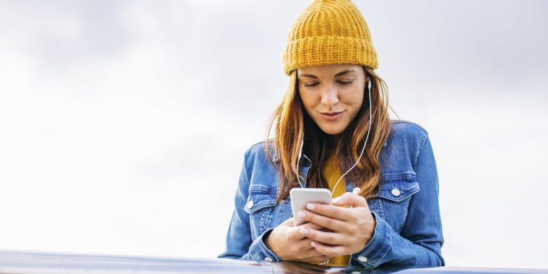 Une femme dehors, portant un bonnet jaune, et faisant le quiz PER sur son téléphone