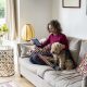 Une femme avec son chien dans son canapé utilisant sa tablette pour simuler des versements volontaires