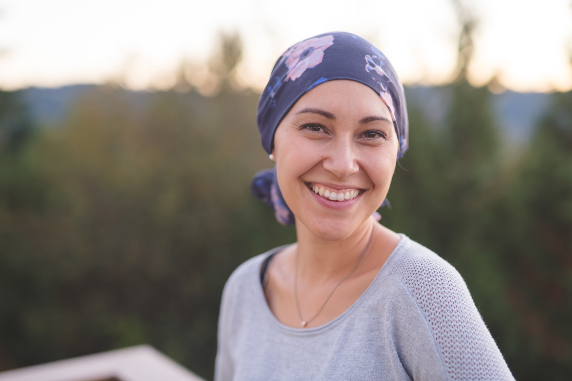 Une femme atteinte d'un cancer avec un bandana sur la tête regardant l'objectif en souriant - bienveillance maladies graves