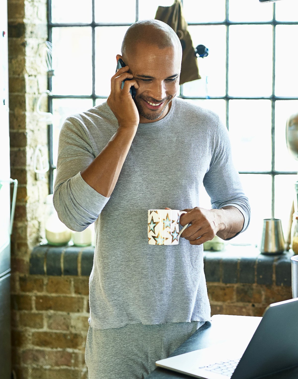 Un homme souriant avec sa tasse à la main discutant au téléphone des freins et motivations de l'épargne salariale