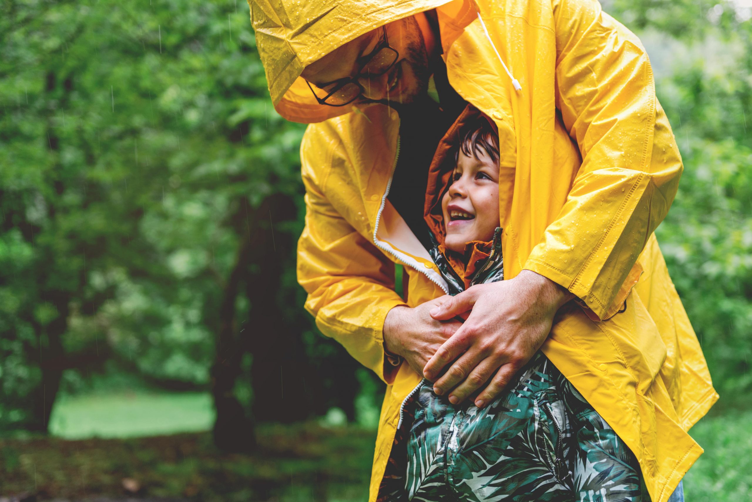 Un père célibataire protégeant son fils de la pluie sous son manteau
