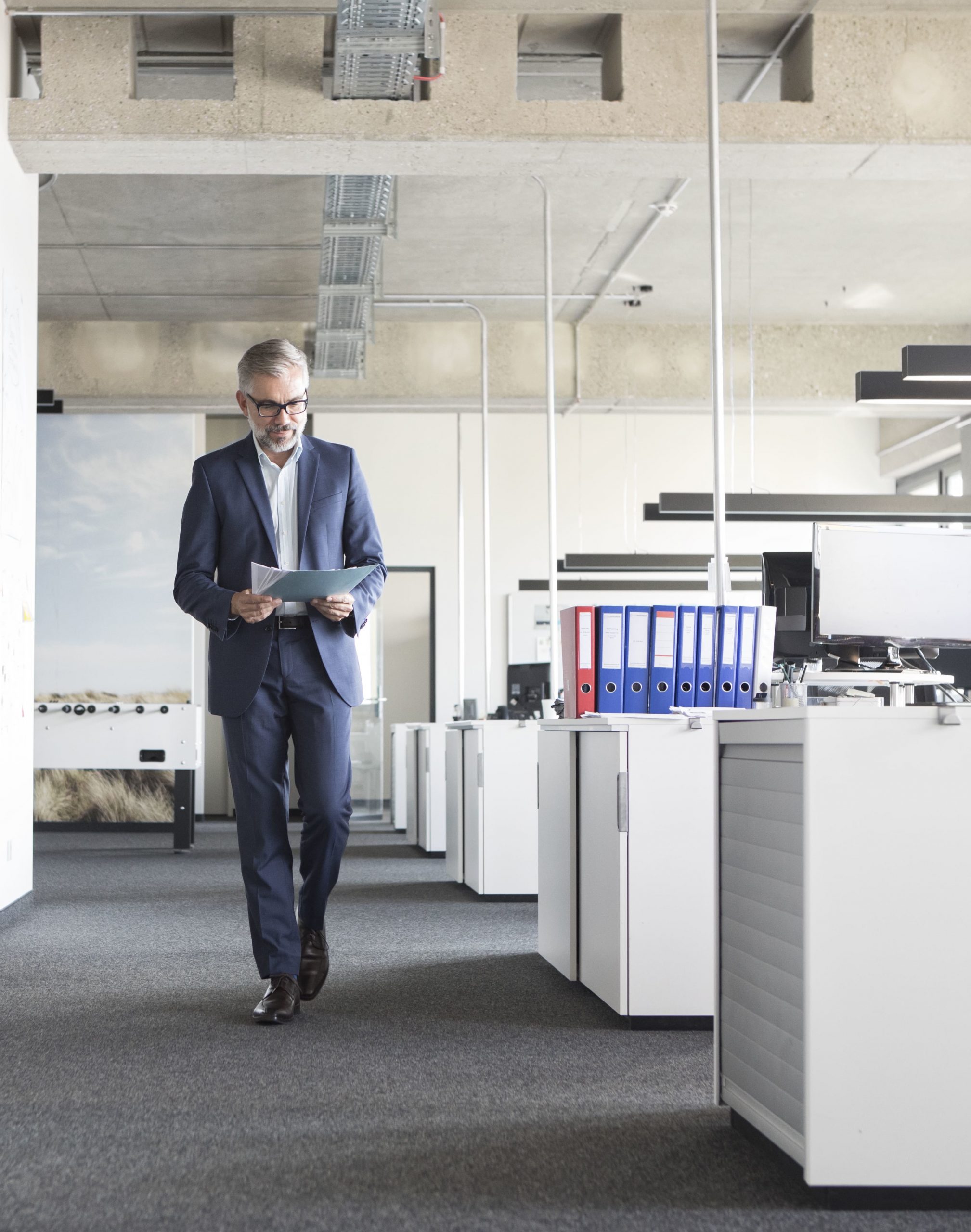 Un homme marchant dans les bureaux et lisant des papiers – absentéisme