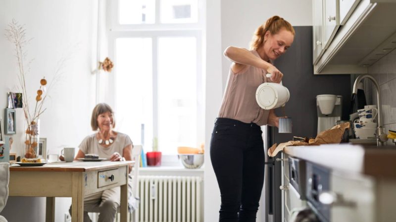 Une femme servant du café à une femme dépendante dans une maison de répit