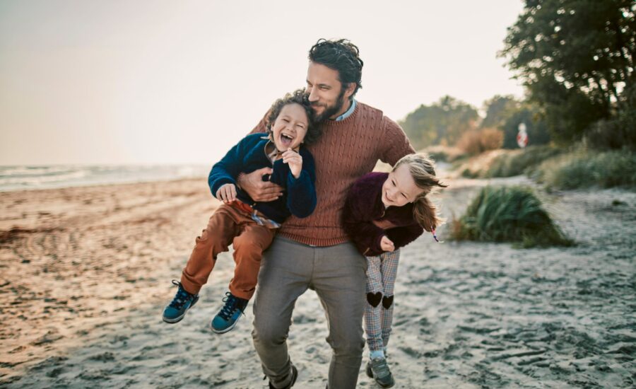 Un homme jouant sur la plage avec ses enfants - prévoyance