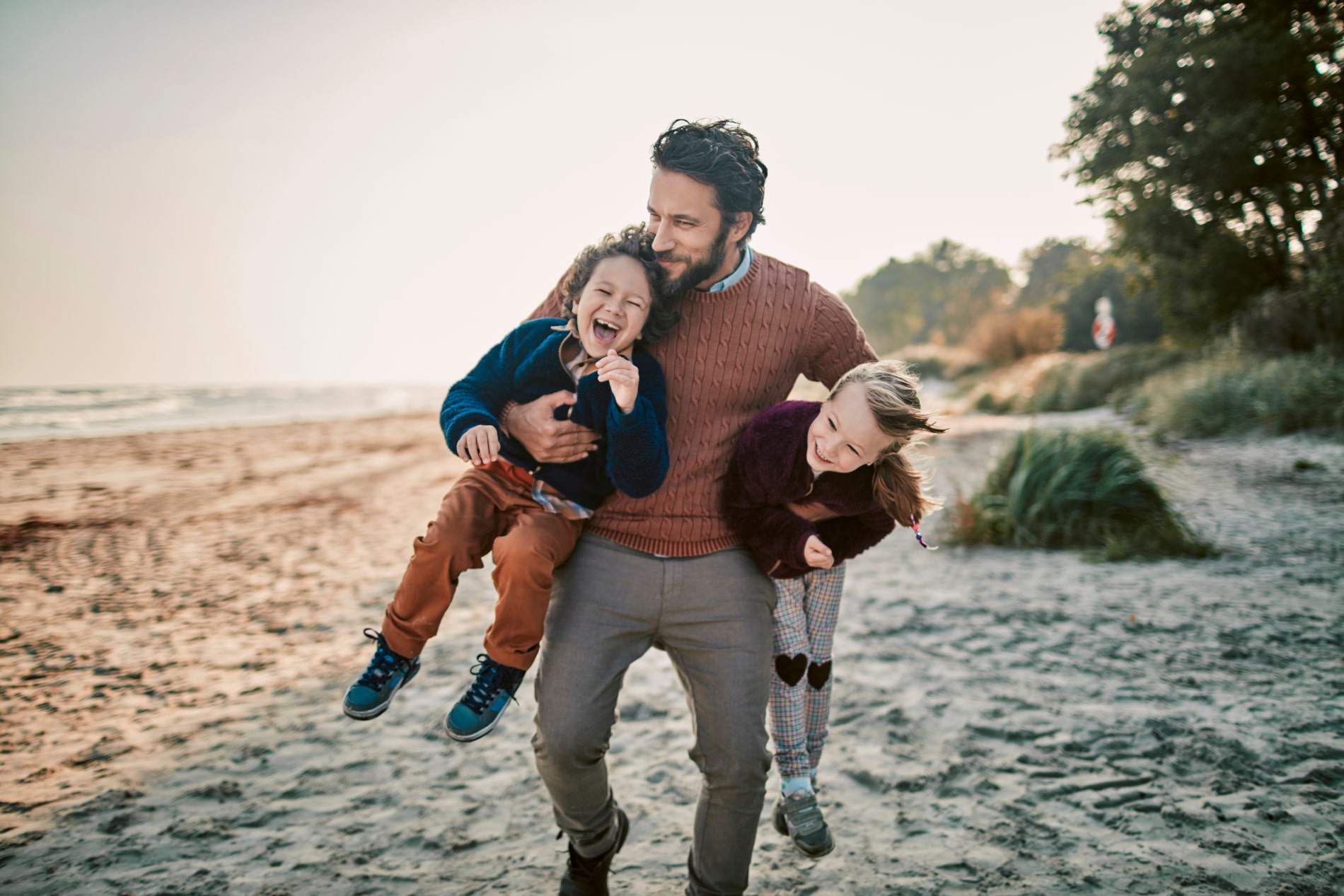Un homme jouant sur la plage avec ses enfants - prévoyance