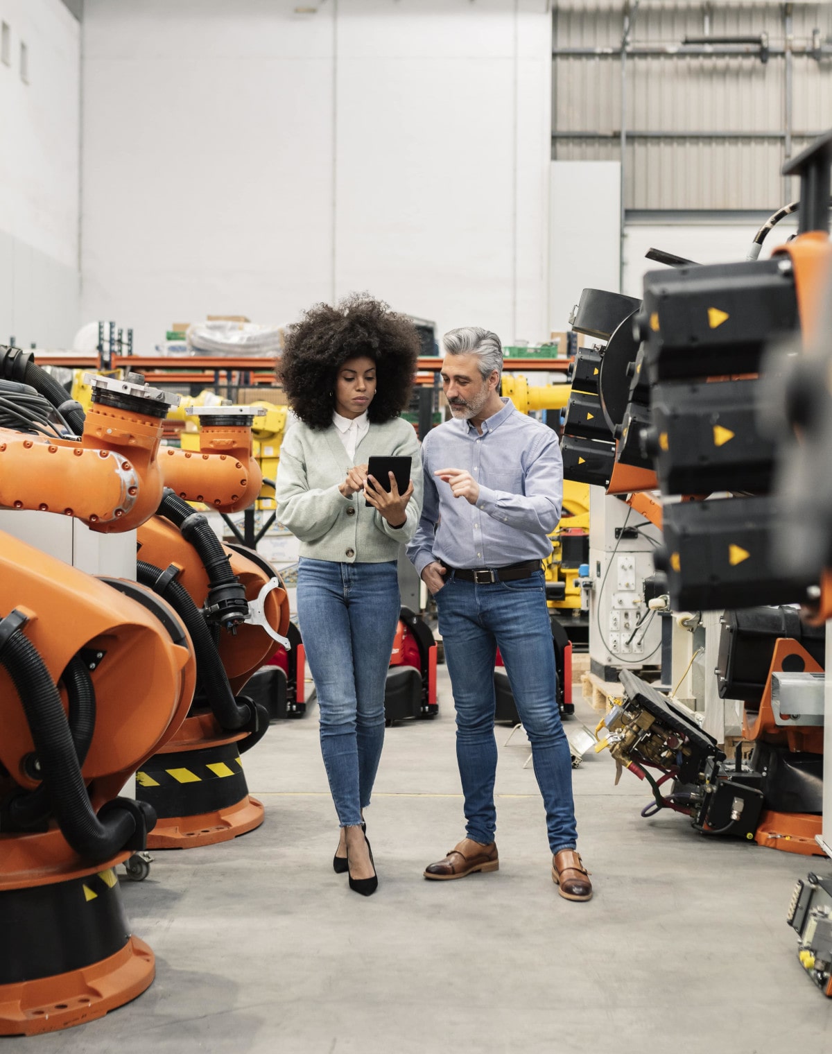 Une femme et un homme regardant une tablette au milieu d’une usine