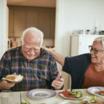 Dépendance - Un couple senior qui rigole en mangeant