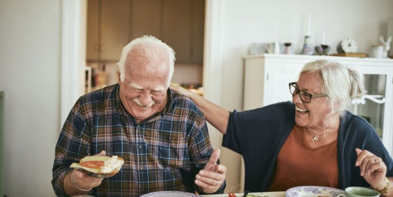 Dépendance - Un couple senior qui rigole en mangeant