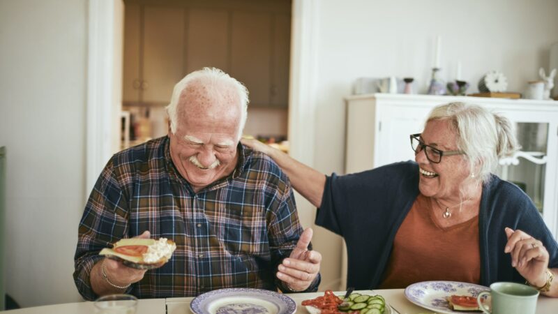 Dépendance - Un couple senior qui rigole en mangeant