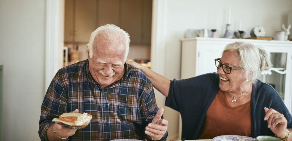 Dépendance - Un couple senior qui rigole en mangeant