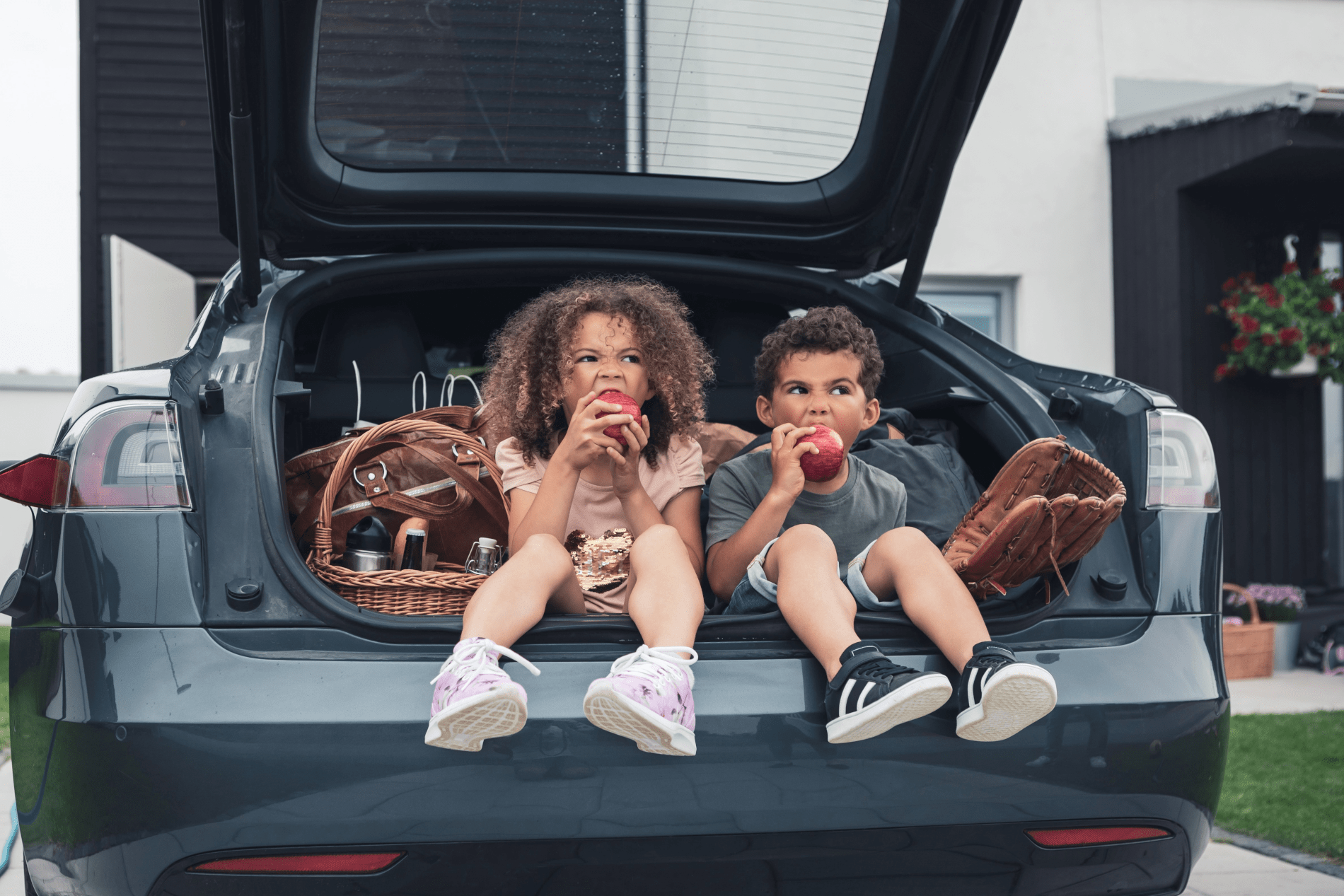 Deux enfants assis dans le coffre d'une voiture mangeant une pomme - prévention obésité