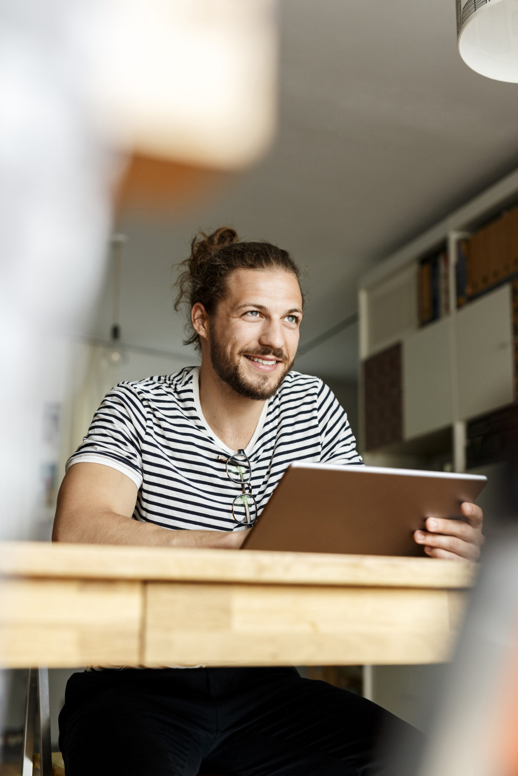 Young man with a bun sitting at home, using tablet Young man with a bun sitting at home, using tablet