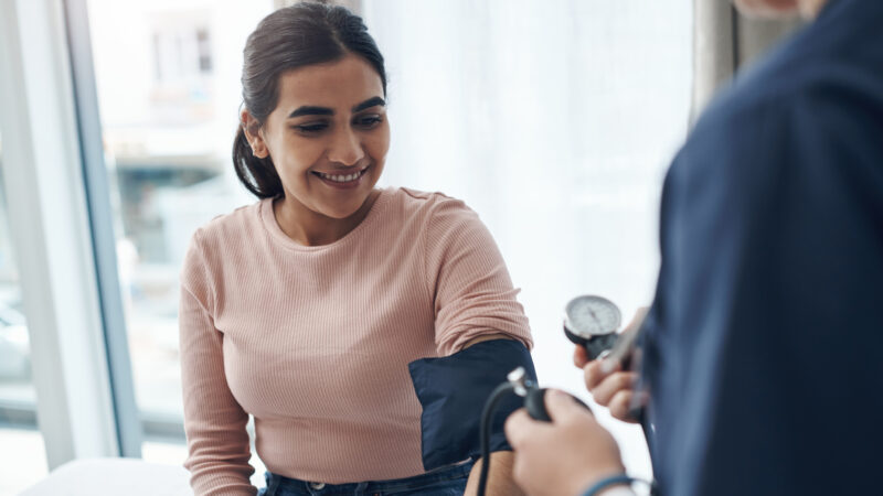 Jeune femme souriante faisant contrôler sa tension