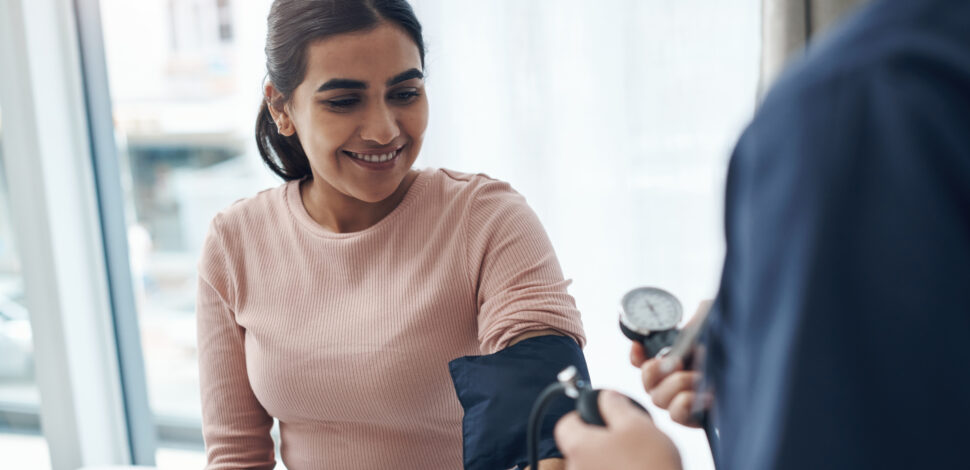 Jeune femme souriante faisant contrôler sa tension Jeune femme souriante faisant contrôler sa tension