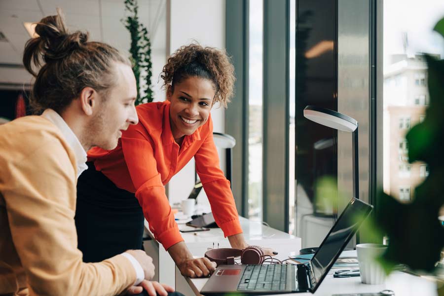 Une femme et un homme au travail discutant devant leur ordinateur - Participation, intéressement